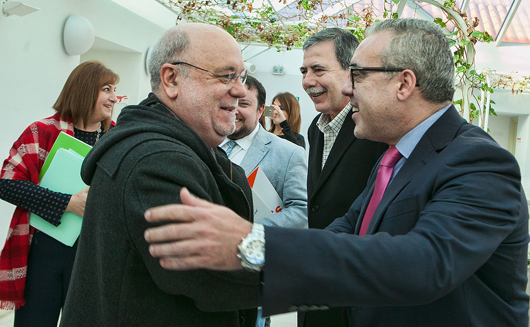 El portavoz regionalista, Pedro Hernando, saluda al consejero de Economía, Hacienda y Empleo, Juan José Sota, a su llegada al Parlamento.
